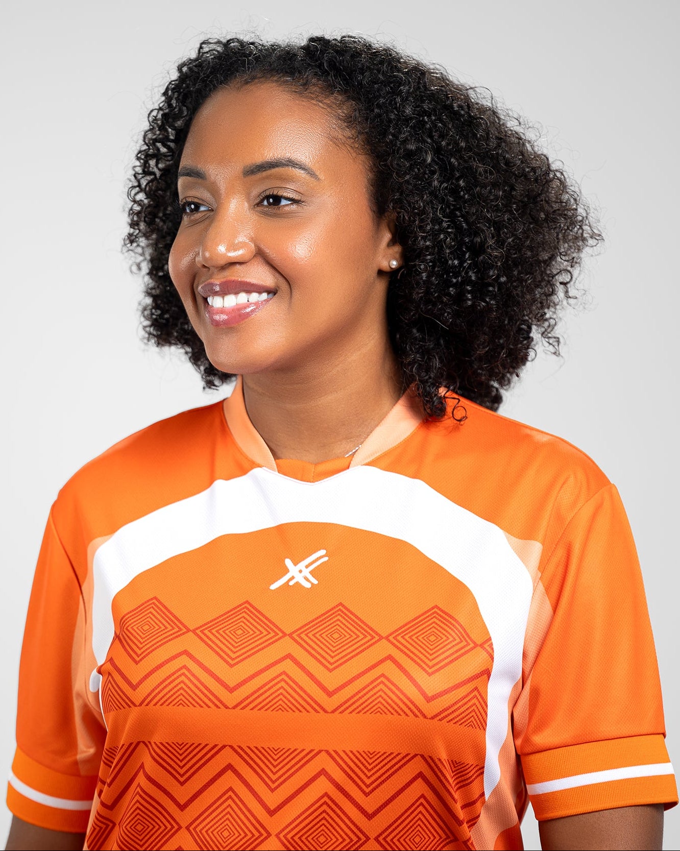 Collection of Person wearing an orange sports jersey with a geometric pattern on a gray background in a gallery layout